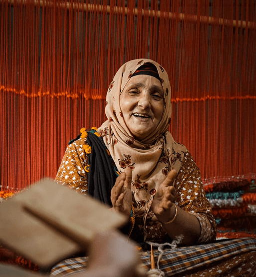 Artisane souriante travaillant devant des fils de tissage colores